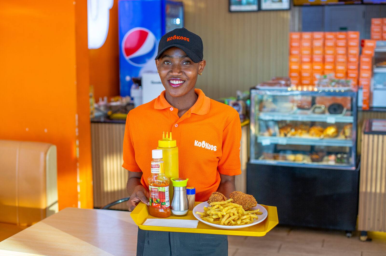 Kookoos team member serving a fresh tray of fried chicken with a smile